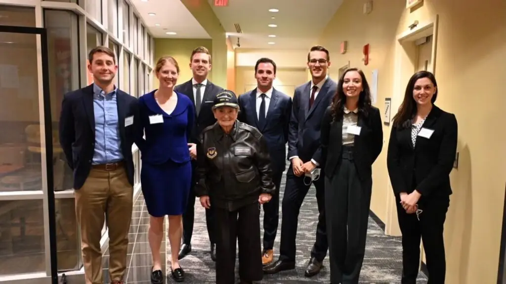 Group of students in business attire standing with Secretary Albright.