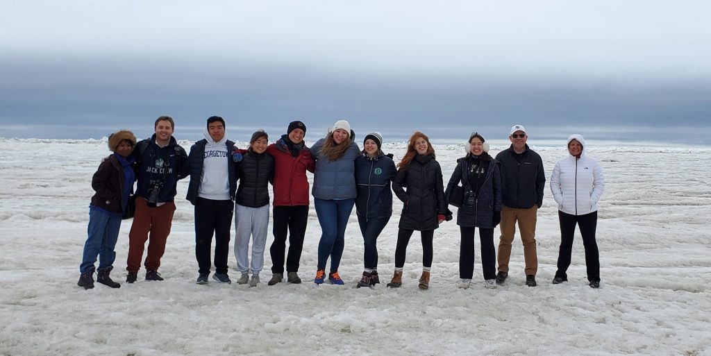 Students and faculty pose for a group photo atop Arctic ice.