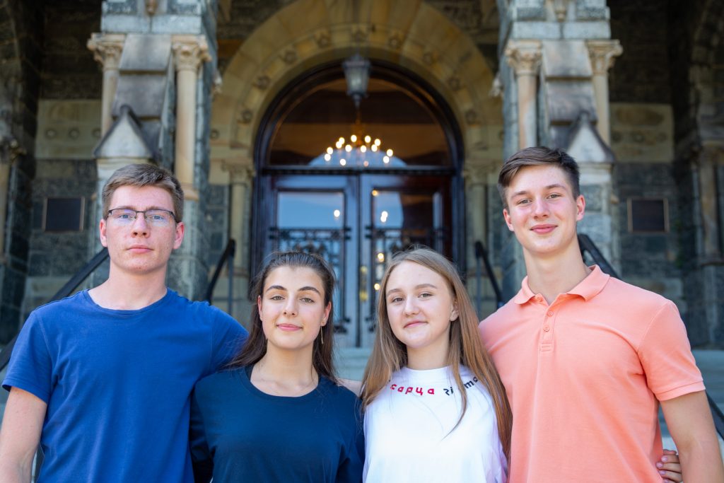 Four Ukrainian Georgetown undergraduates smile together in front of Healy Hall