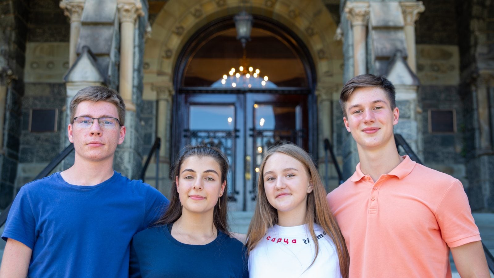 Four Ukrainian Georgetown undergraduates smile together in front of Healy Hall
