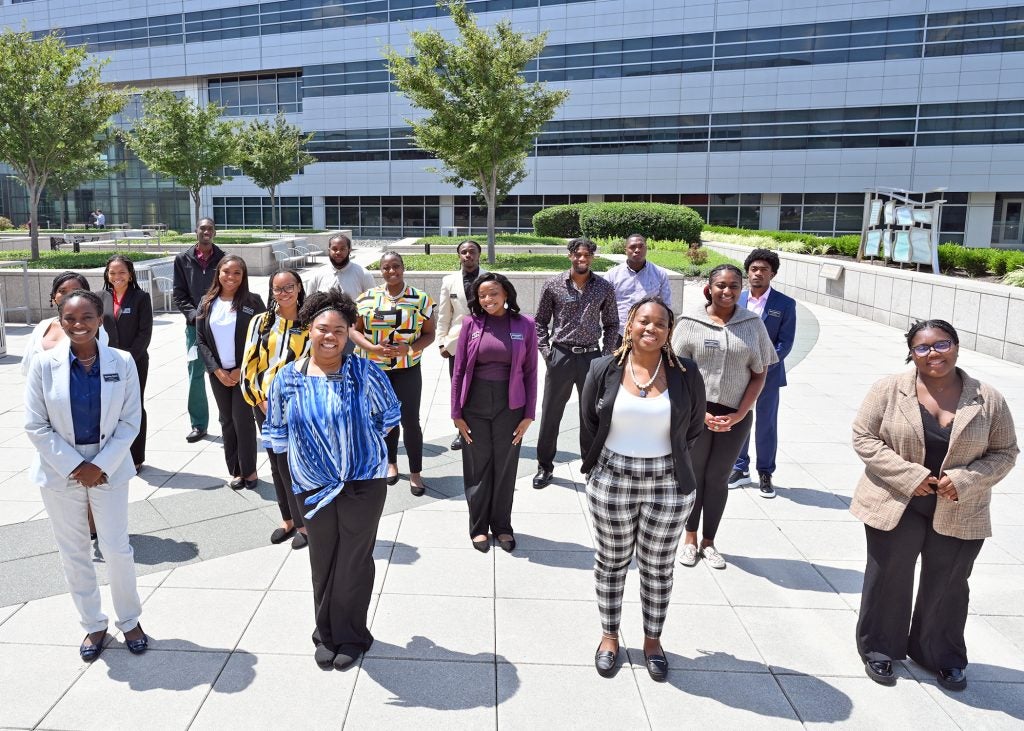 Program participants stand in four rows outside