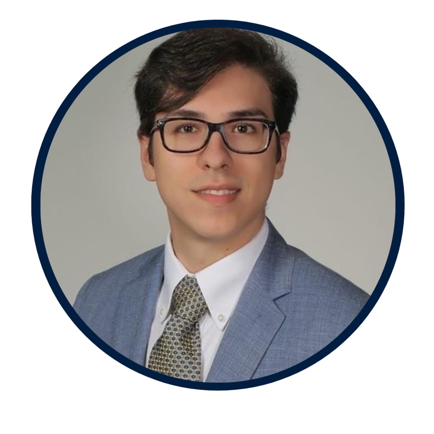 Arlind Ferhati Headshot, wearing black-rimmed glasses, a gray blazer, white shirt, and tan tie.