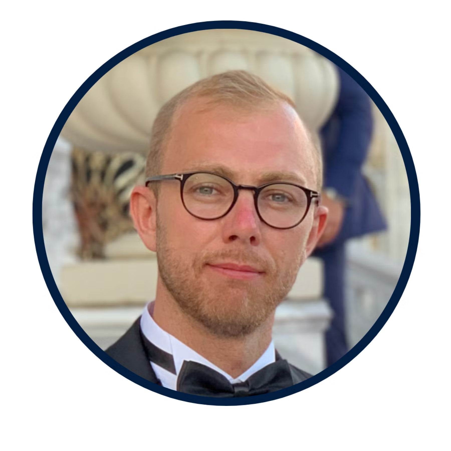 Henrik Schildt Lundberg Headshot, wearing black-rimmed glasses and a black tuxedo.