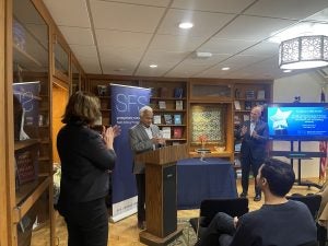 Shanta Devarajan finishes his remarks at the podium and receives applause from members of the audience in McGhee Library