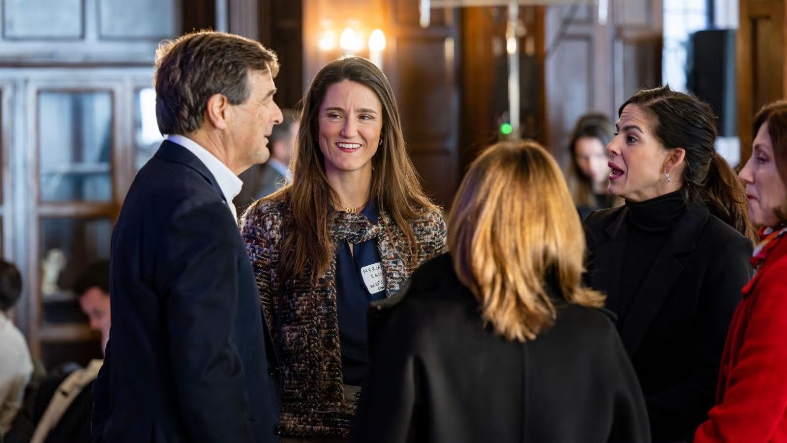 Discussion between two women and one man standing casually.