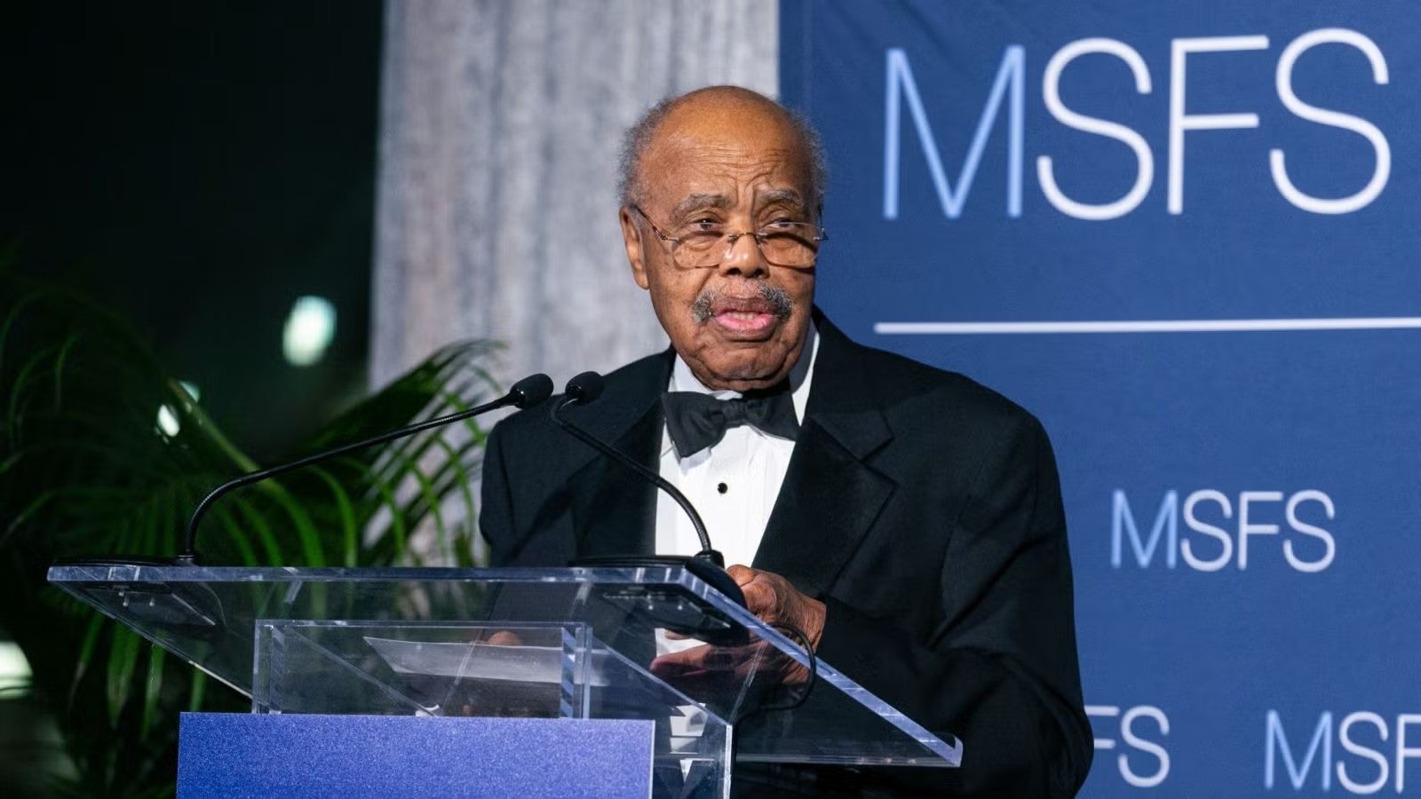 Ambassador Donald McHenry in black tuxedo standing at podium during gala.