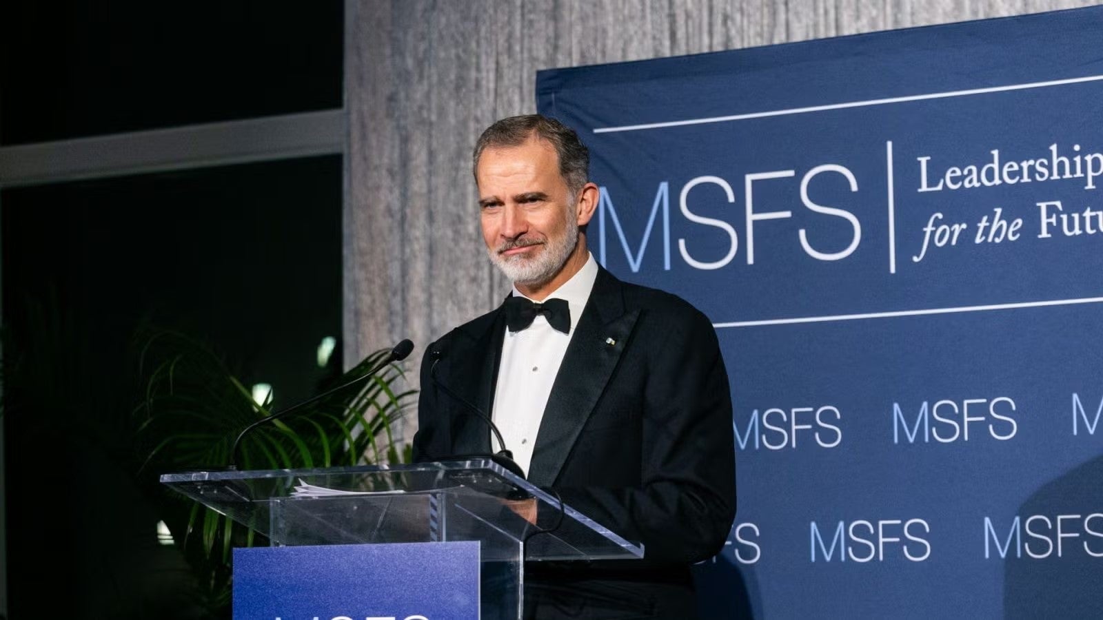 King Felipe standing at podium in black formalwear during gala.