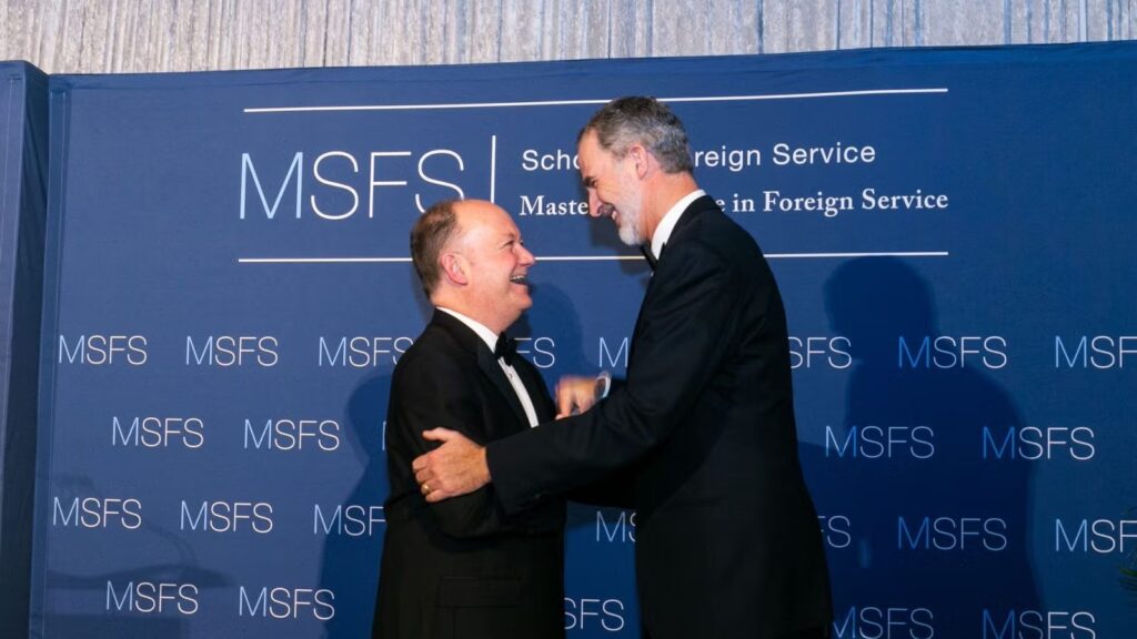 President DeGioia and King Felipe standing in black formalwear shaking hands at gala.
