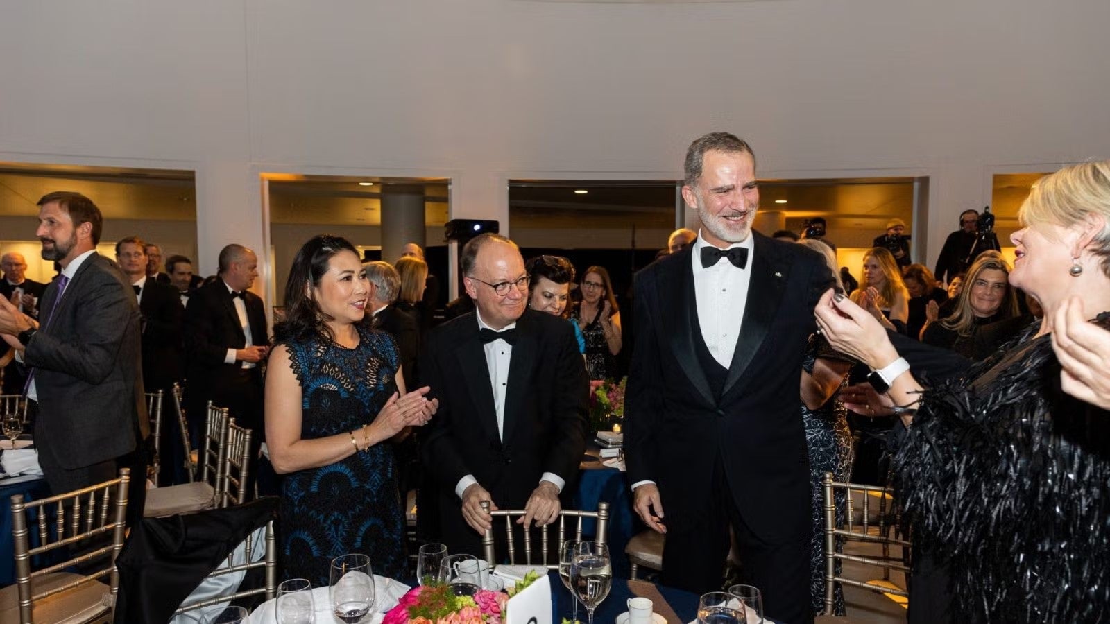 King Felipe and President DeGioia standing together in formalwear by table during gala.
