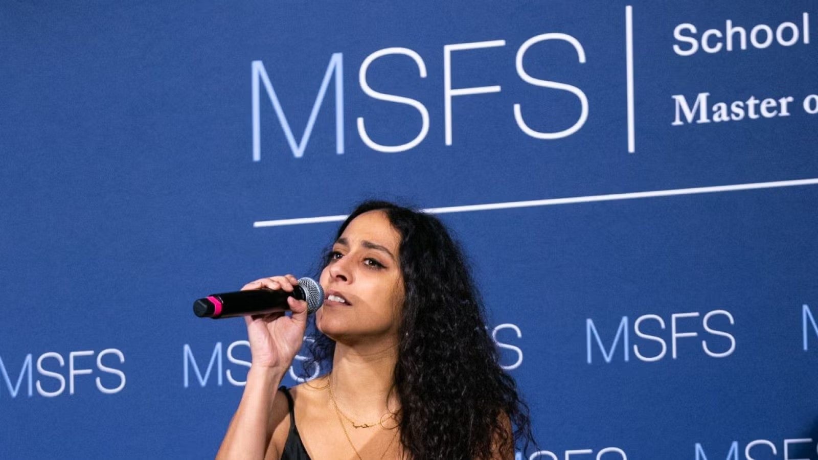 Sylvia Yacoub standing with microphone in hand, singing at gala.