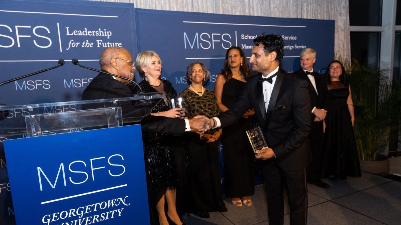 Award recipient shaking hands with Ambassador McHenry at gala.