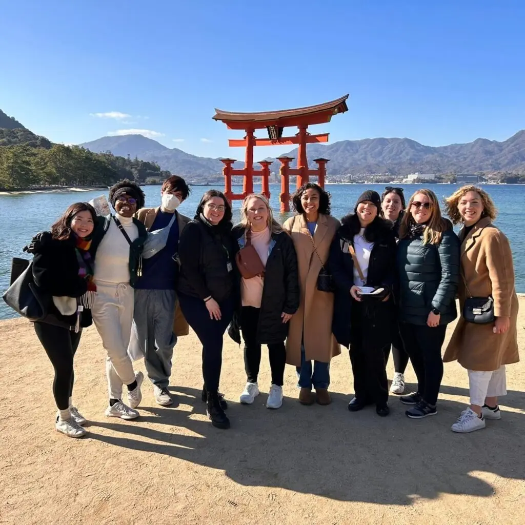 Jasmin Alsaied on study abroad trip to Japan with other students, all wearing warm outerwear. Clear blue skies and mountains are pictured behind them.