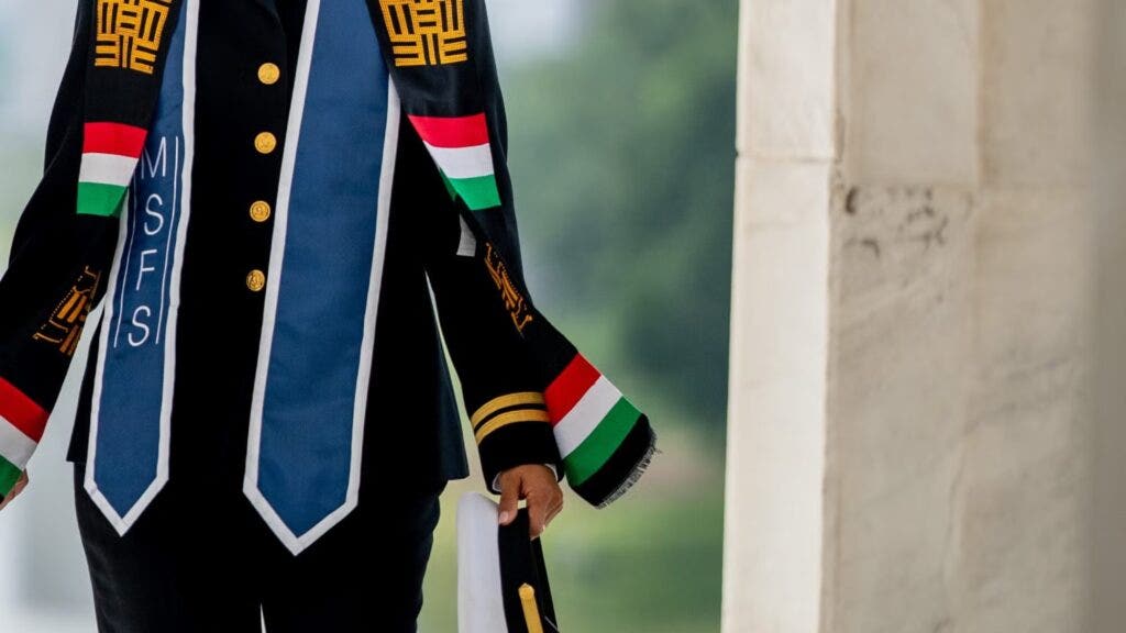 Military Officer, Jasmin Alsaied in formal military dress with blue commencement stole around her neck, holding her uniform hat.