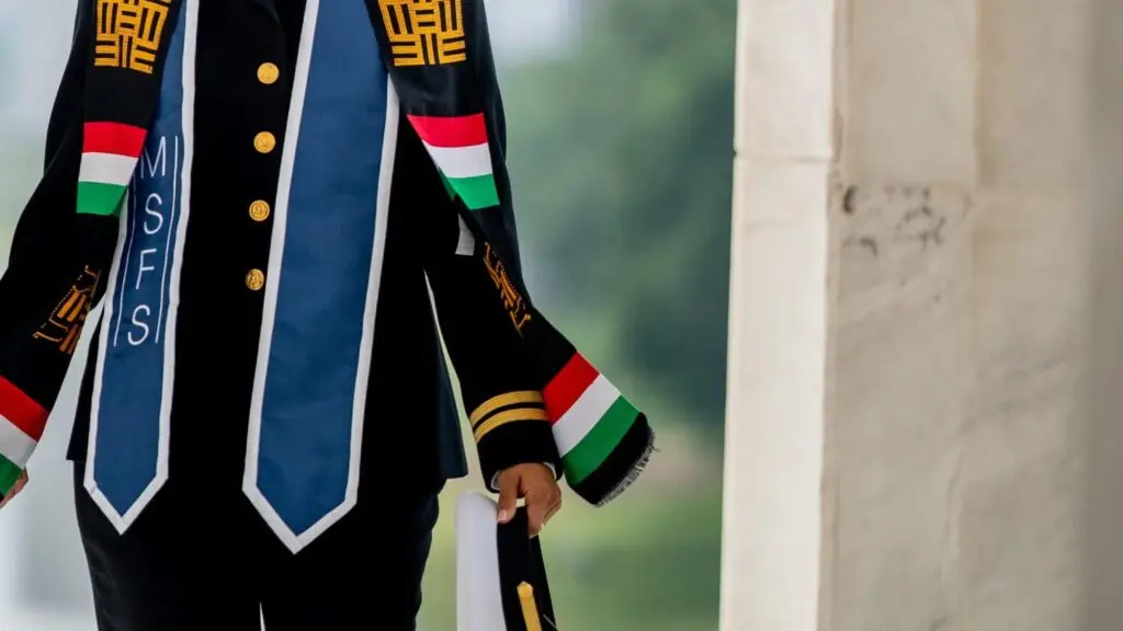 Military Officer, Jasmin Alsaied in formal military dress with blue commencement stole around her neck, holding her uniform hat.