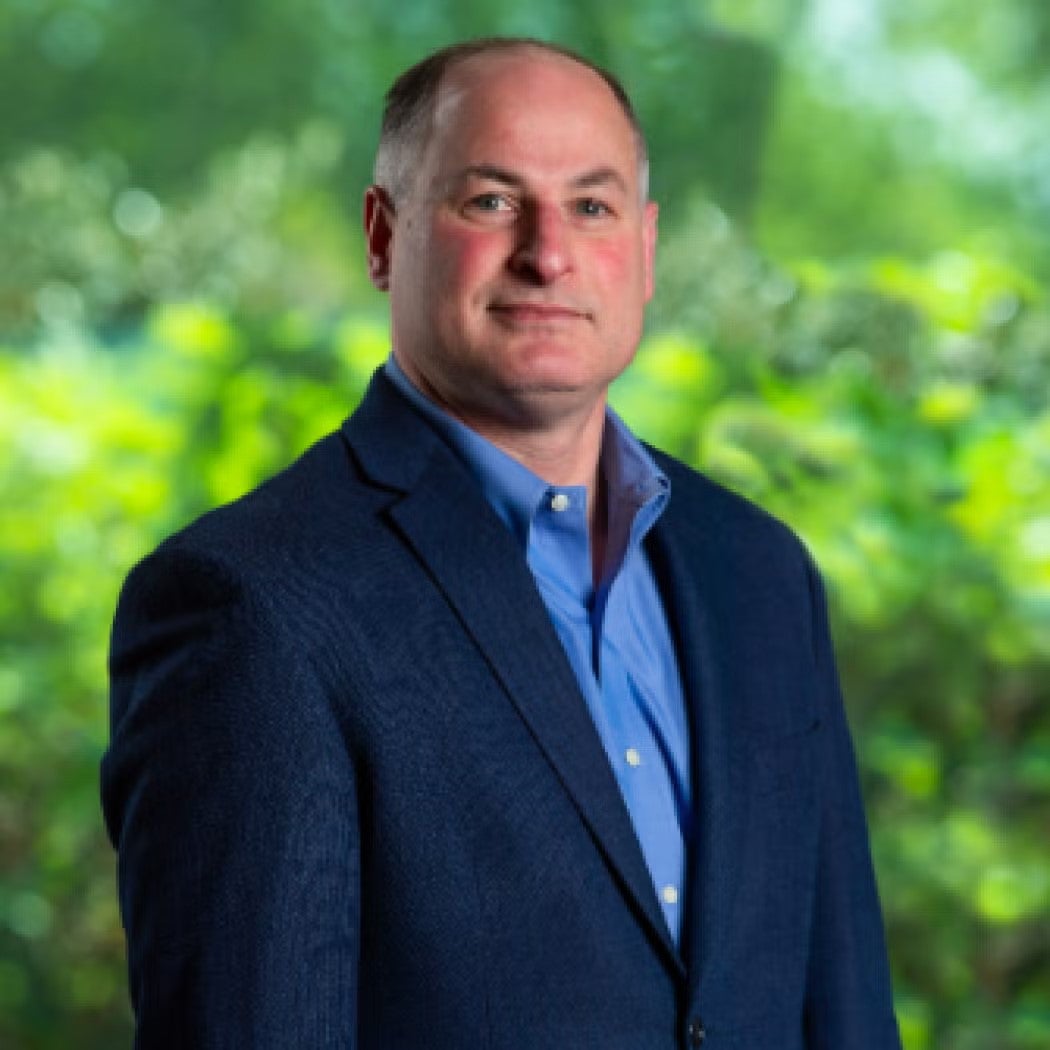 Alan Dinerman Headshot in navy blue blazer and dark blue shirt.
