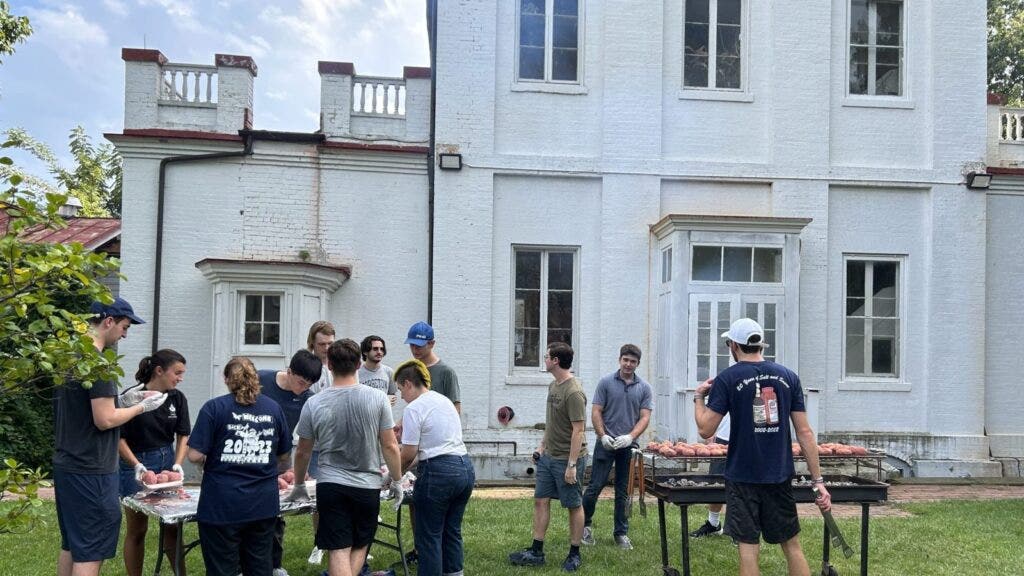 A group of people putting food on grills outside.