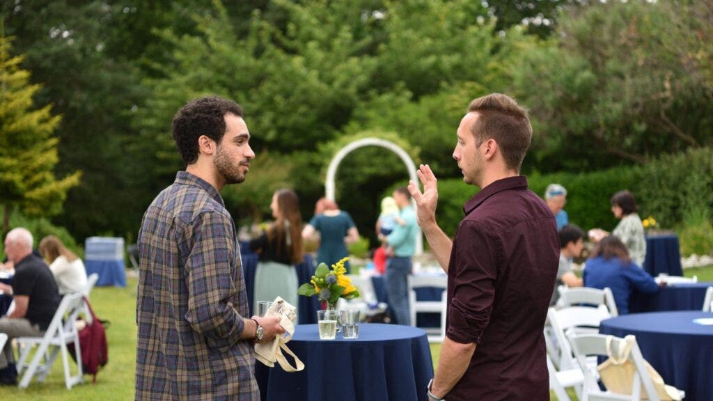 Two people standing at a high top table talking. 