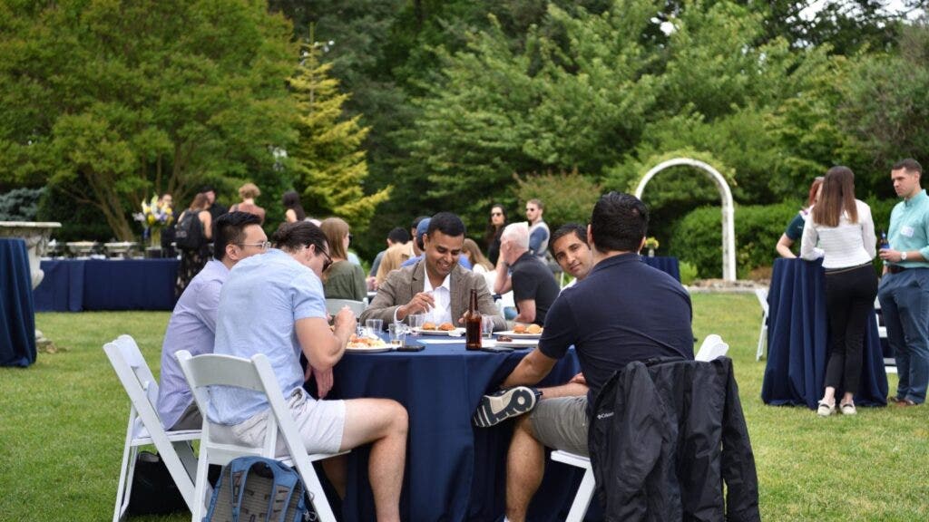A group of people sitting at a table outside talking and smiling.