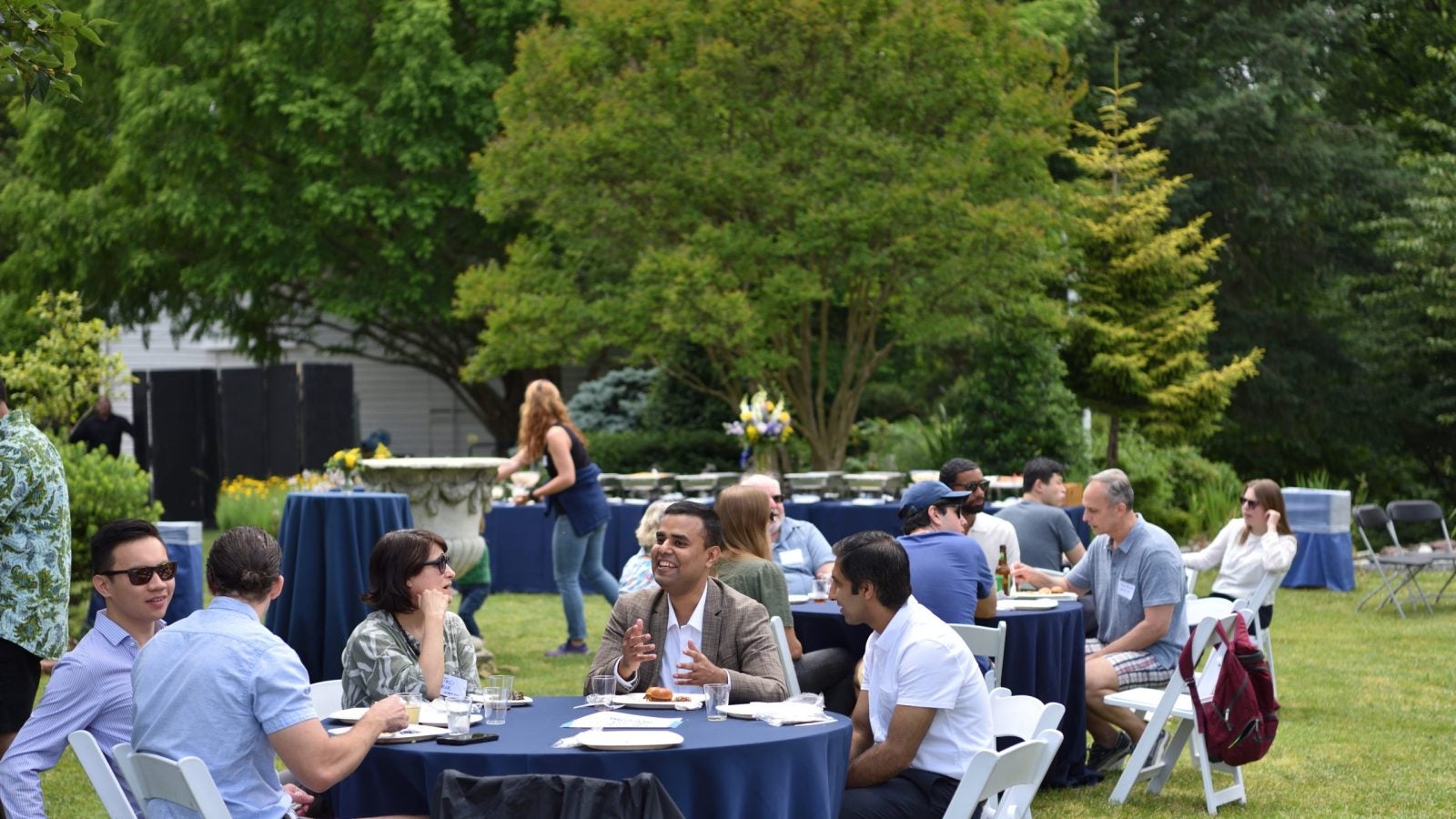 A group of people sitting at a table outside talking and smiling