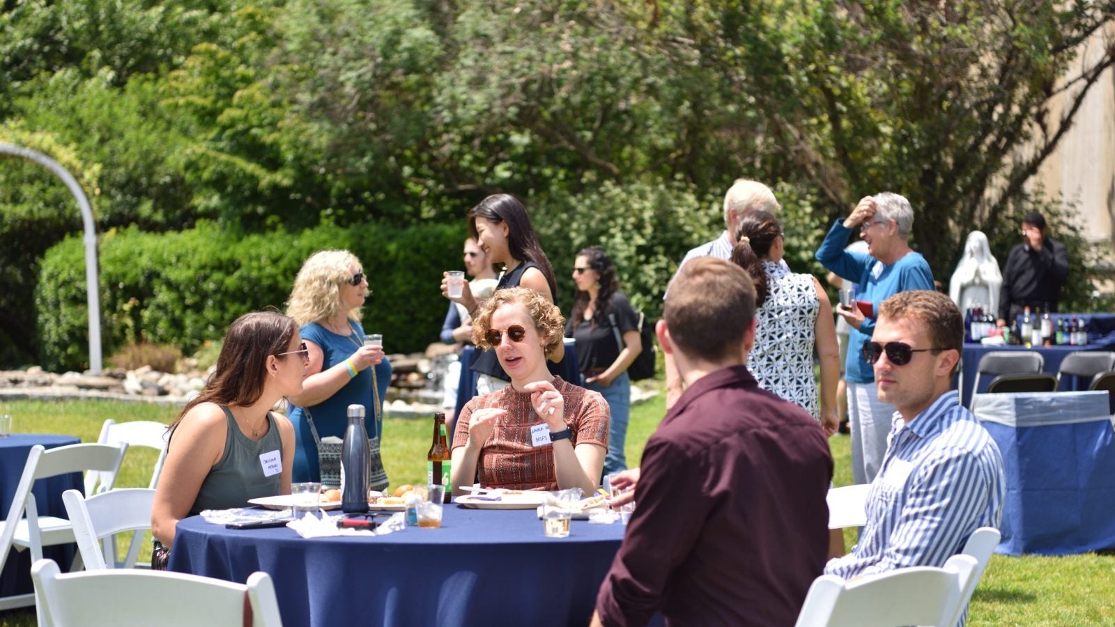A group of people sitting at a table outside talking and smiling