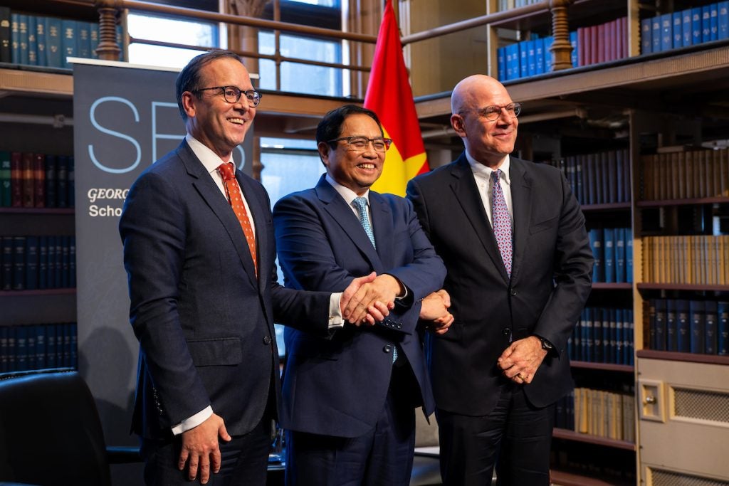 Prime Minister Phạm Minh Chính shakes hands with Dean Joel Hellman and Professor Evan Medeiros.