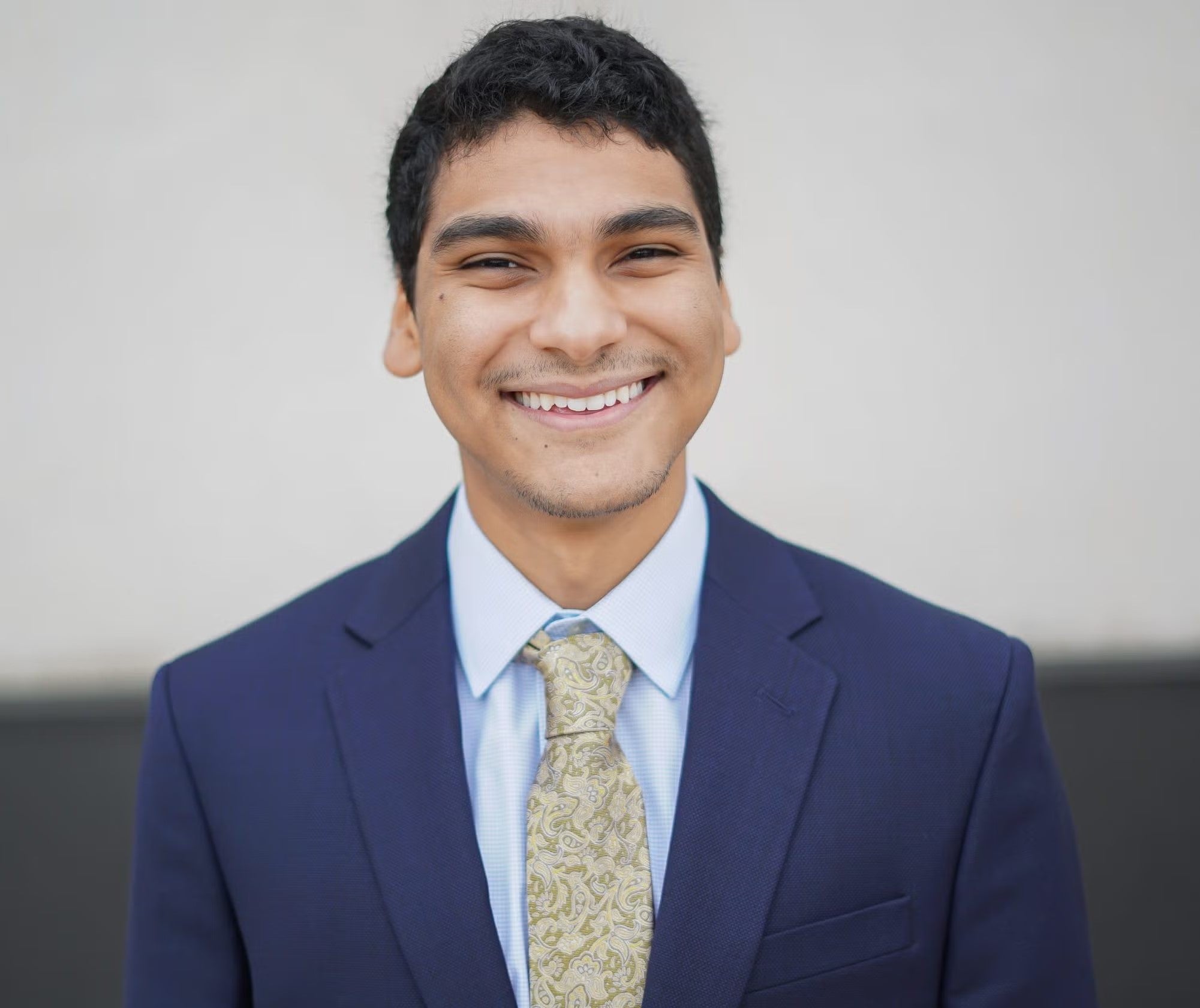 Adham Fattah headshot wearing navy blue blazer, light blue shirt, and pale yellow tie.