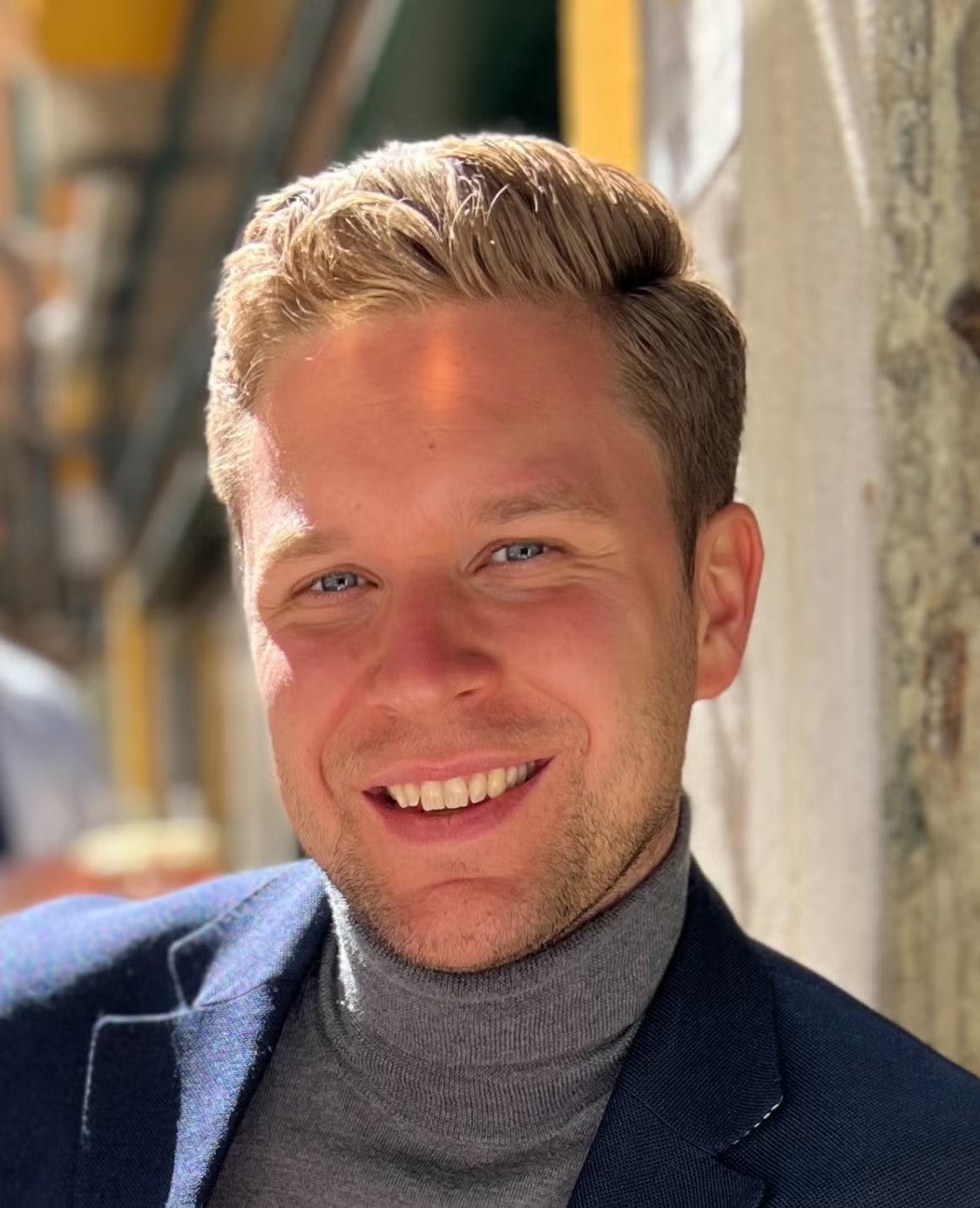 Philipp Sandmann headshot. He is wearing a dark gray turtleneck and a navy blue blazer.