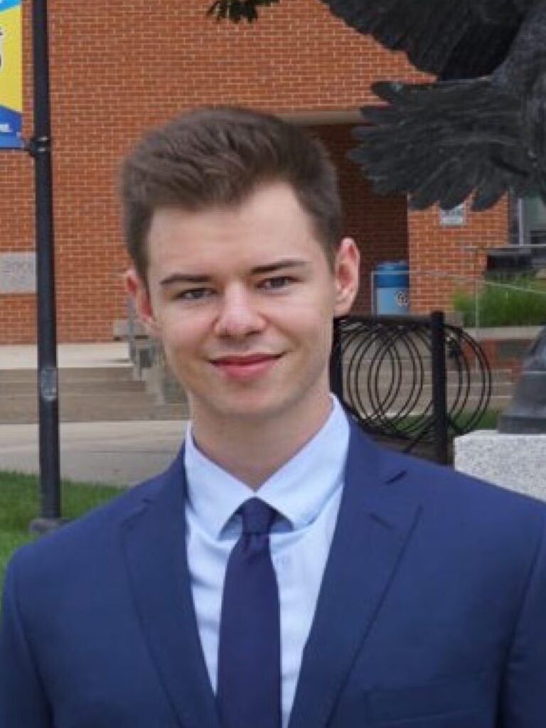 Jonah Gosnay wearing a blue suit and tie with a light blue button-down shirt.