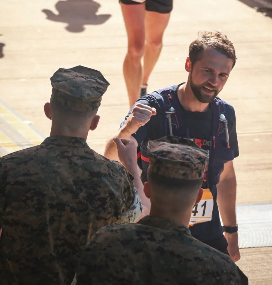 A participant receiving a thumbs-up from a U.S. Marine after a race.