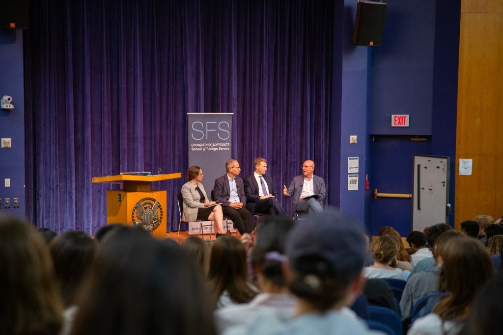 SFS students fill the seats of ICC Auditorium. SFS Professors Renanah Joyce, Charles Kupchan, and Matthew Kroenig join SFS Dean Hellman on stage.