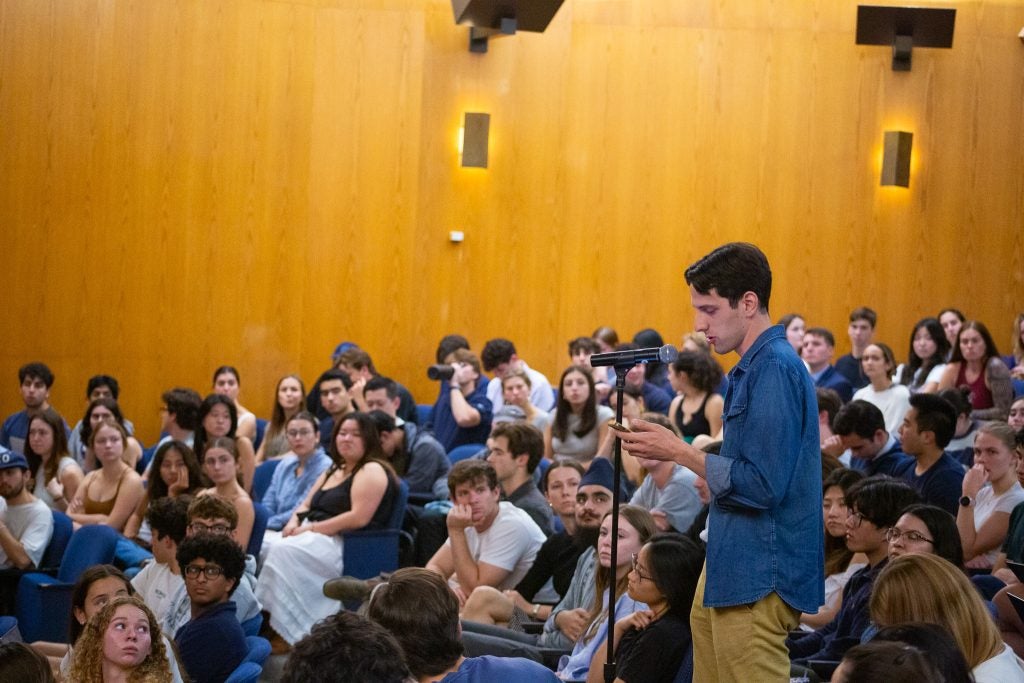 An SFS student stands at a microphone to pose a question to the panel