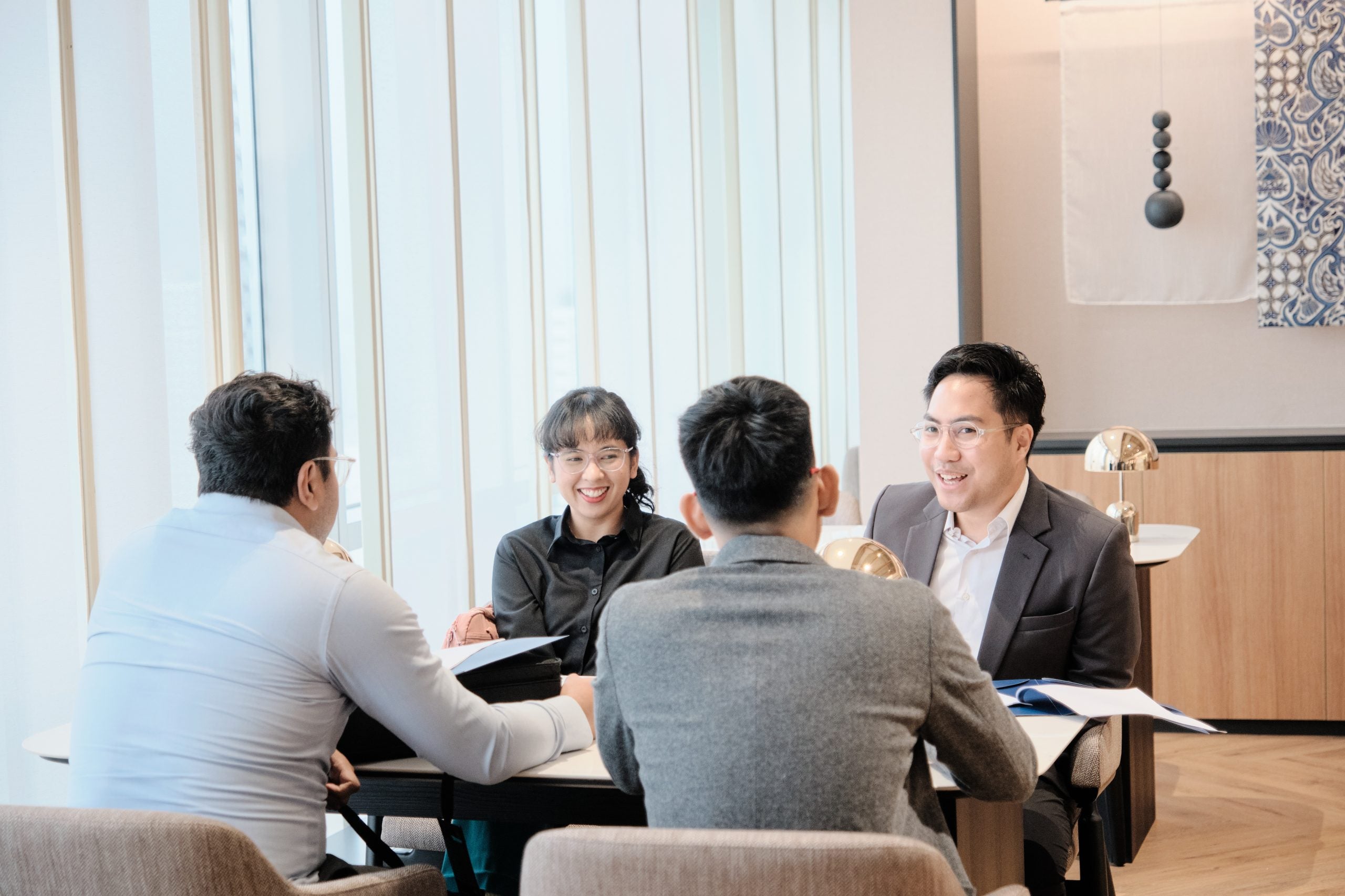 Four smiling students sitting around a table having a conversation