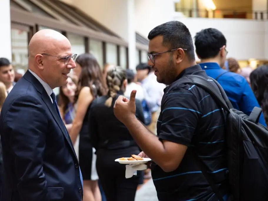 A student and a professor chatting at an event.