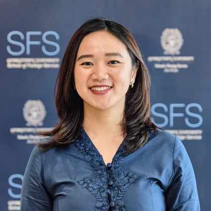 Headshot of Anna Maria Jesica smiling in front of Georgetown SFS Asia Pacific backdrop
