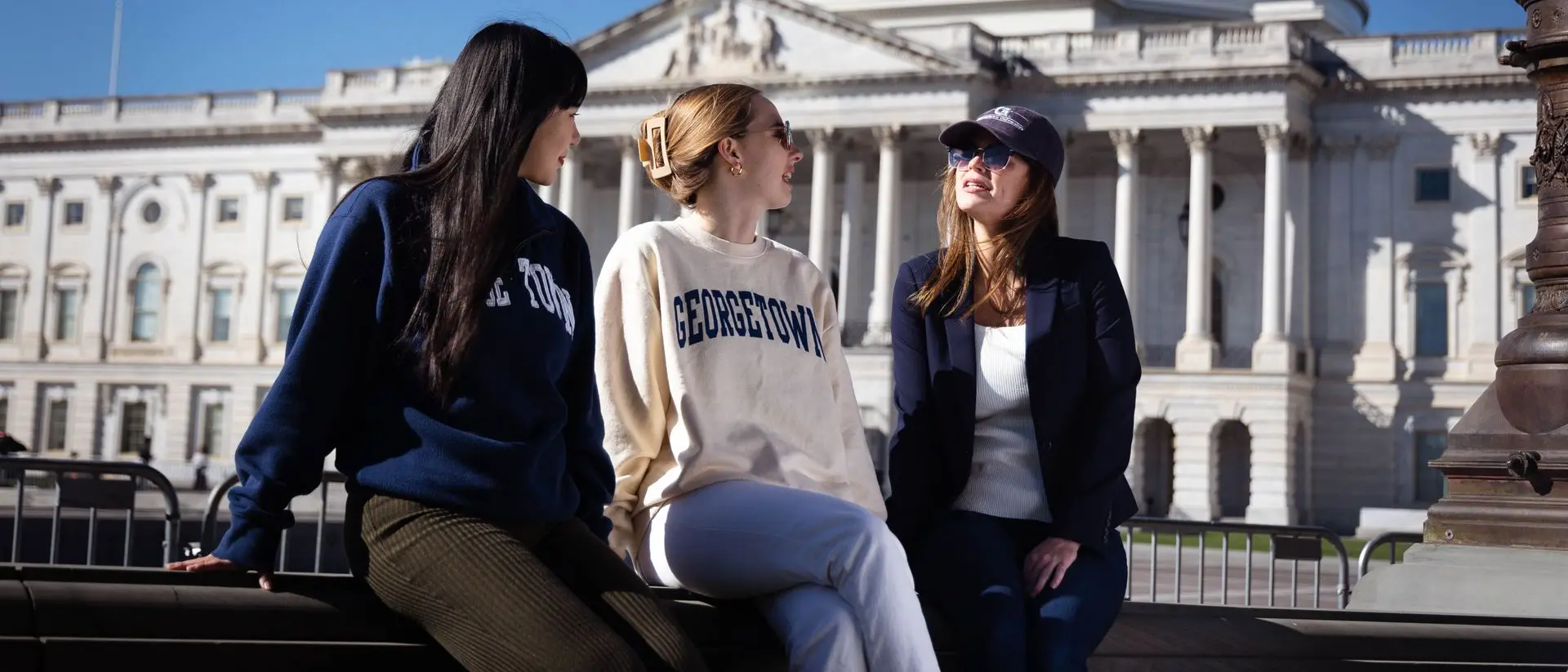 Three students sitting and talking in front of the US Capitol Building.