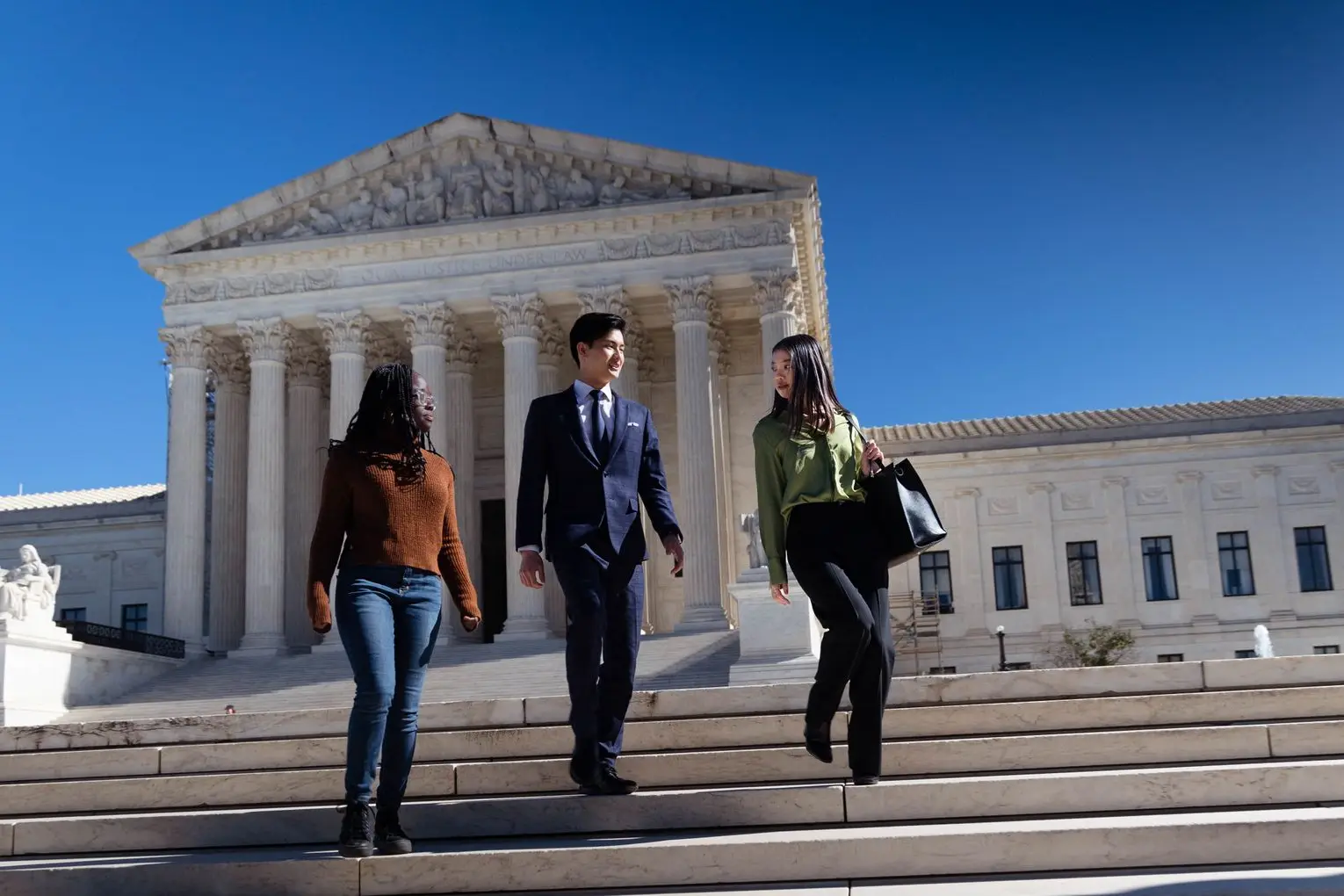 Three students walk down the steps of the US Supreme Court.