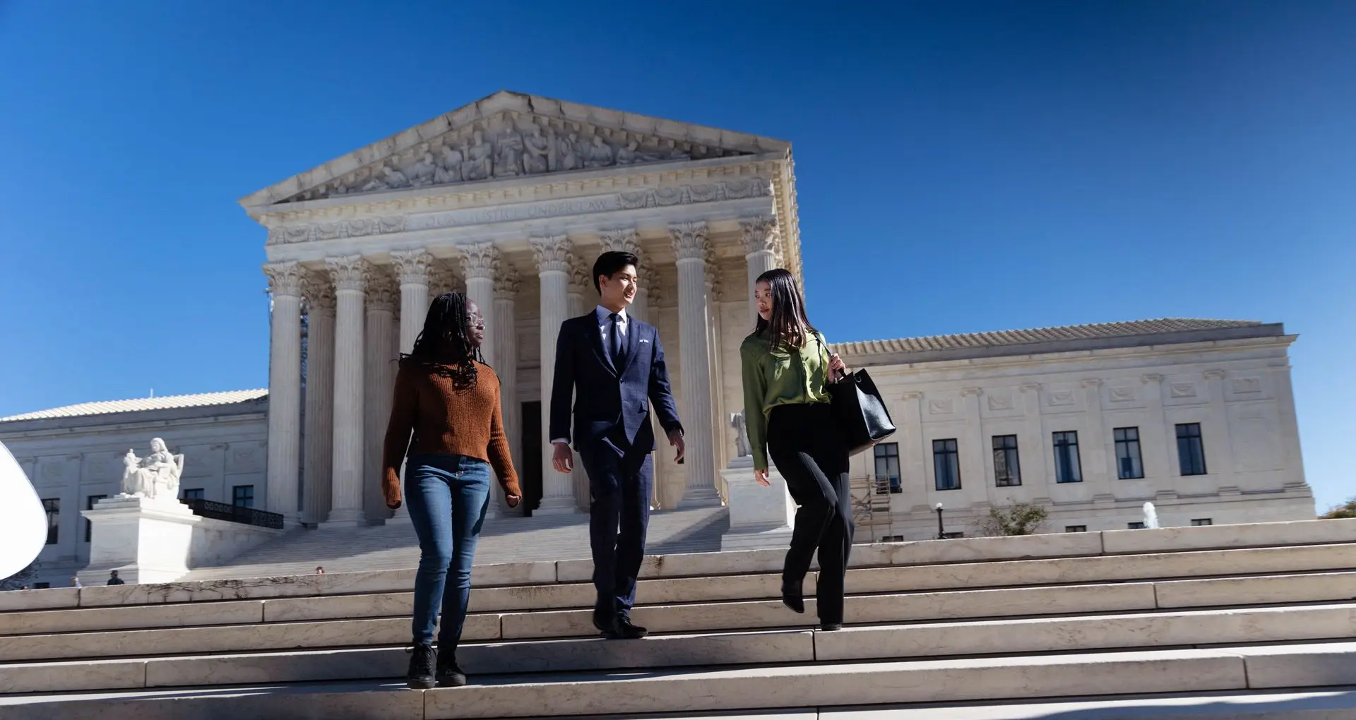 Three students walk down the steps of the US Supreme Court.