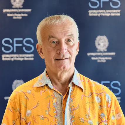 Headshot of Scott Guggenheim smiling in front of Georgetown SFS Asia Pacific backdrop