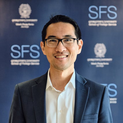 Headshot of Yuhki Tajima smiling in front of Georgetown SFS Asia Pacific backdrop