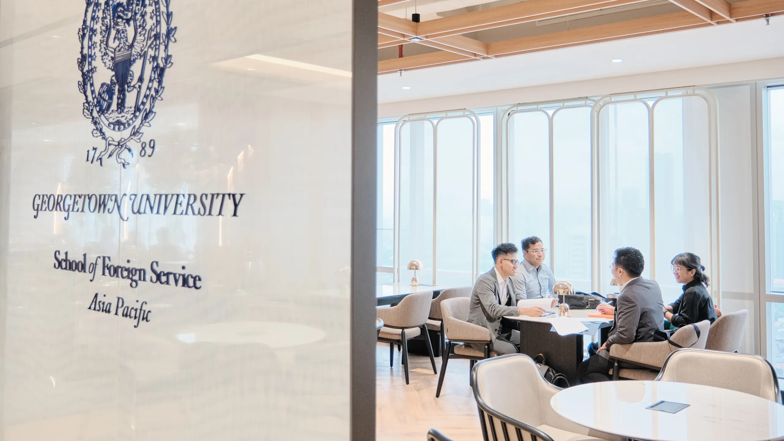 Fours students having a conversation sitting around a table at the Georgetown Asia Pacific branch location