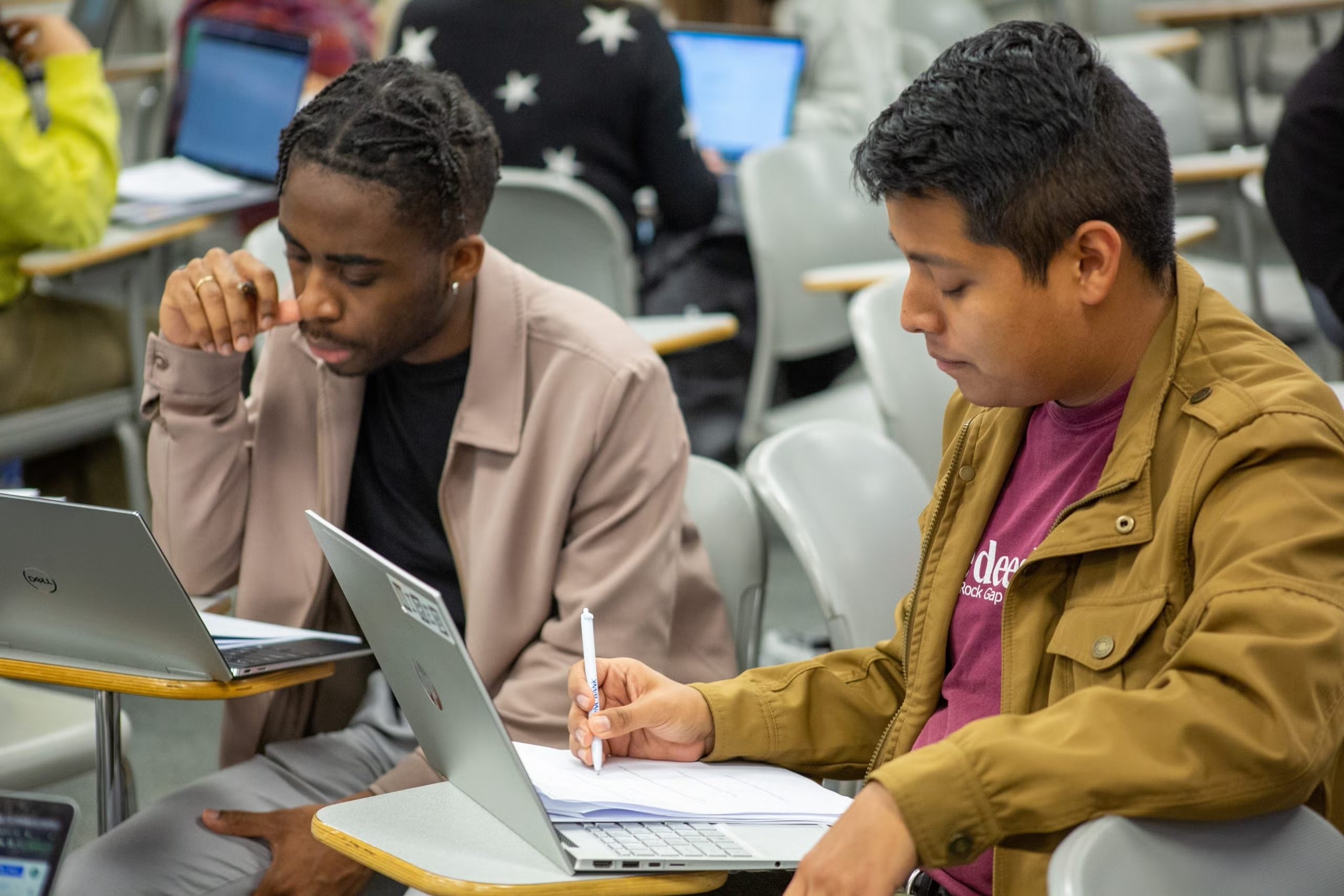 Two students take notes while discussing the case study they received in Visner's STIA 391 class.