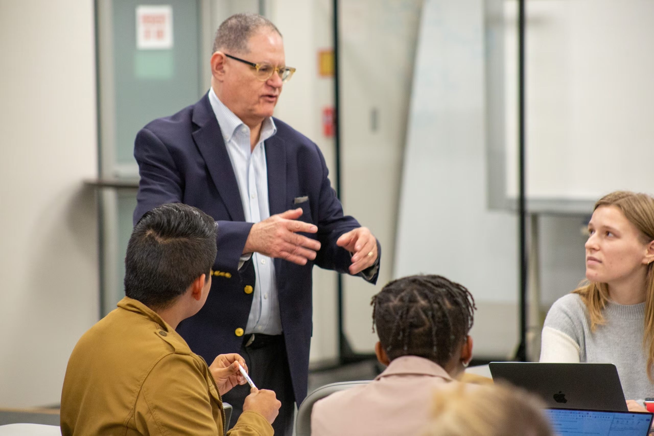 Visner speaks to three students who are seated around a table in his STIA 391 class.