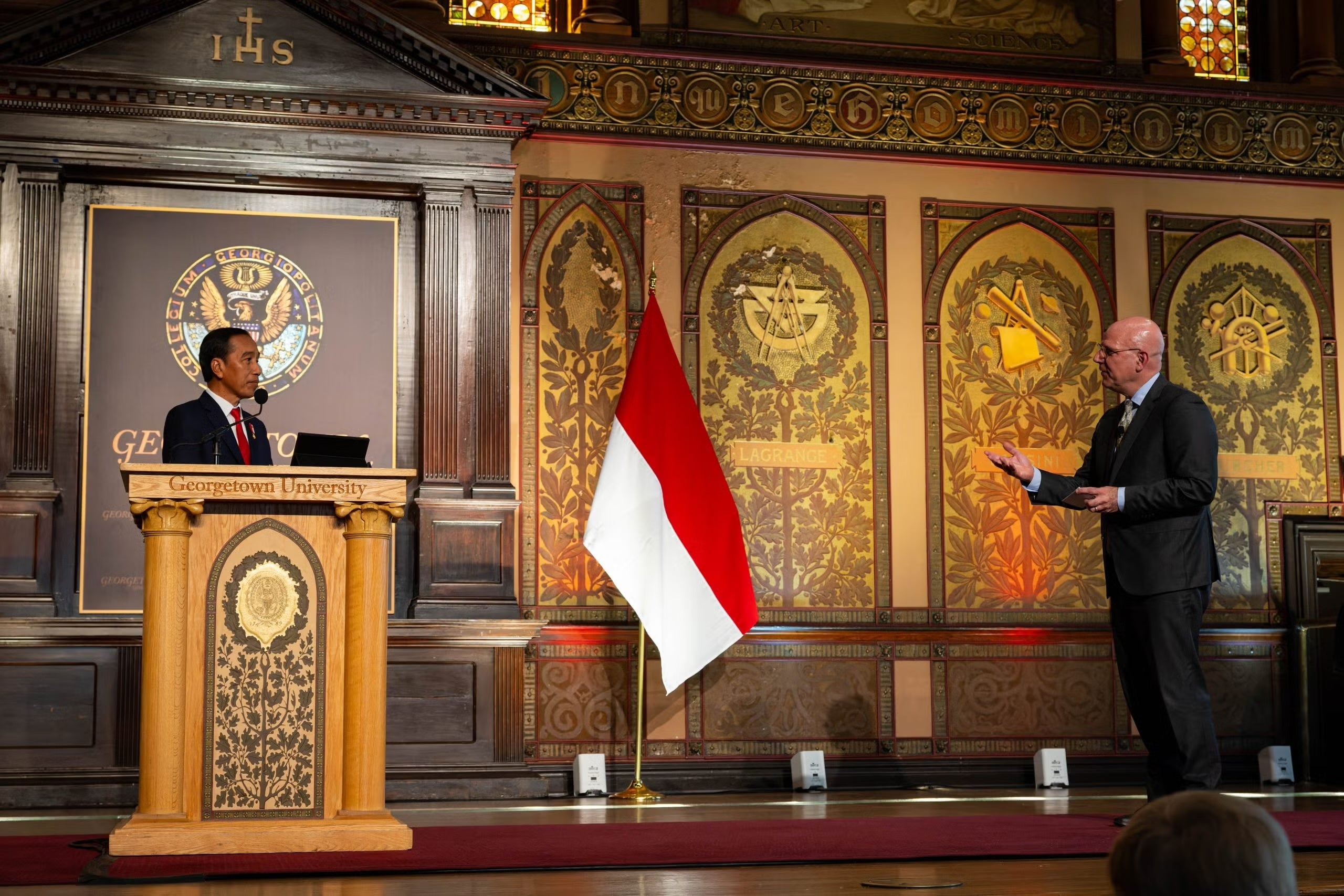 President Joko Widodo and Joel Hellman on the Gaston Hall stage with an Indonesian flag.