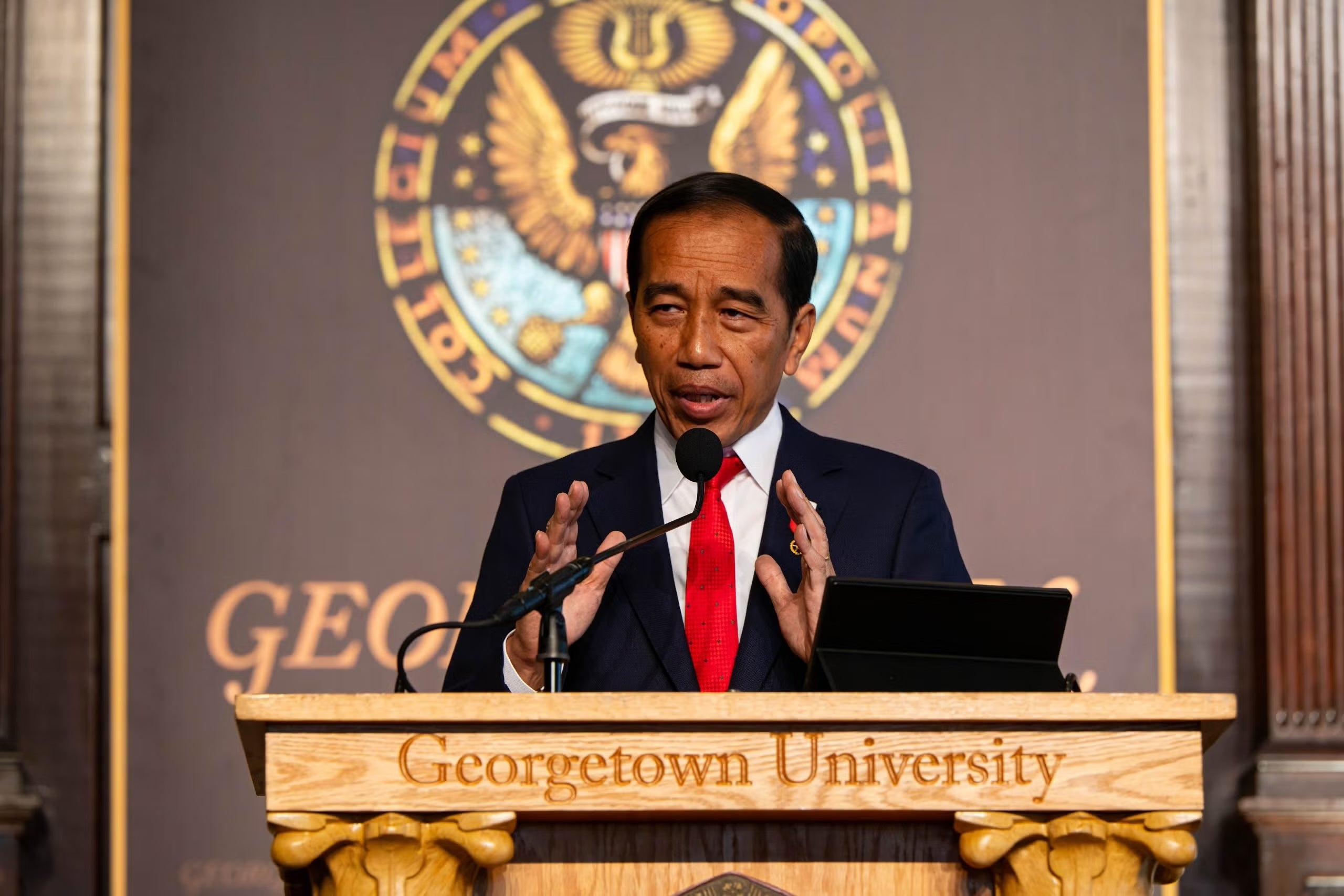 President Joko Widodo speaking at a Georgetown University podium on the stage of Gaston Hall.