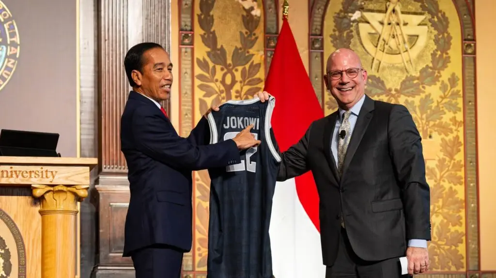President Joko Widodo and Joel Hellman on the stage of Gaston Hall holding a jersey saying "Jokowi"