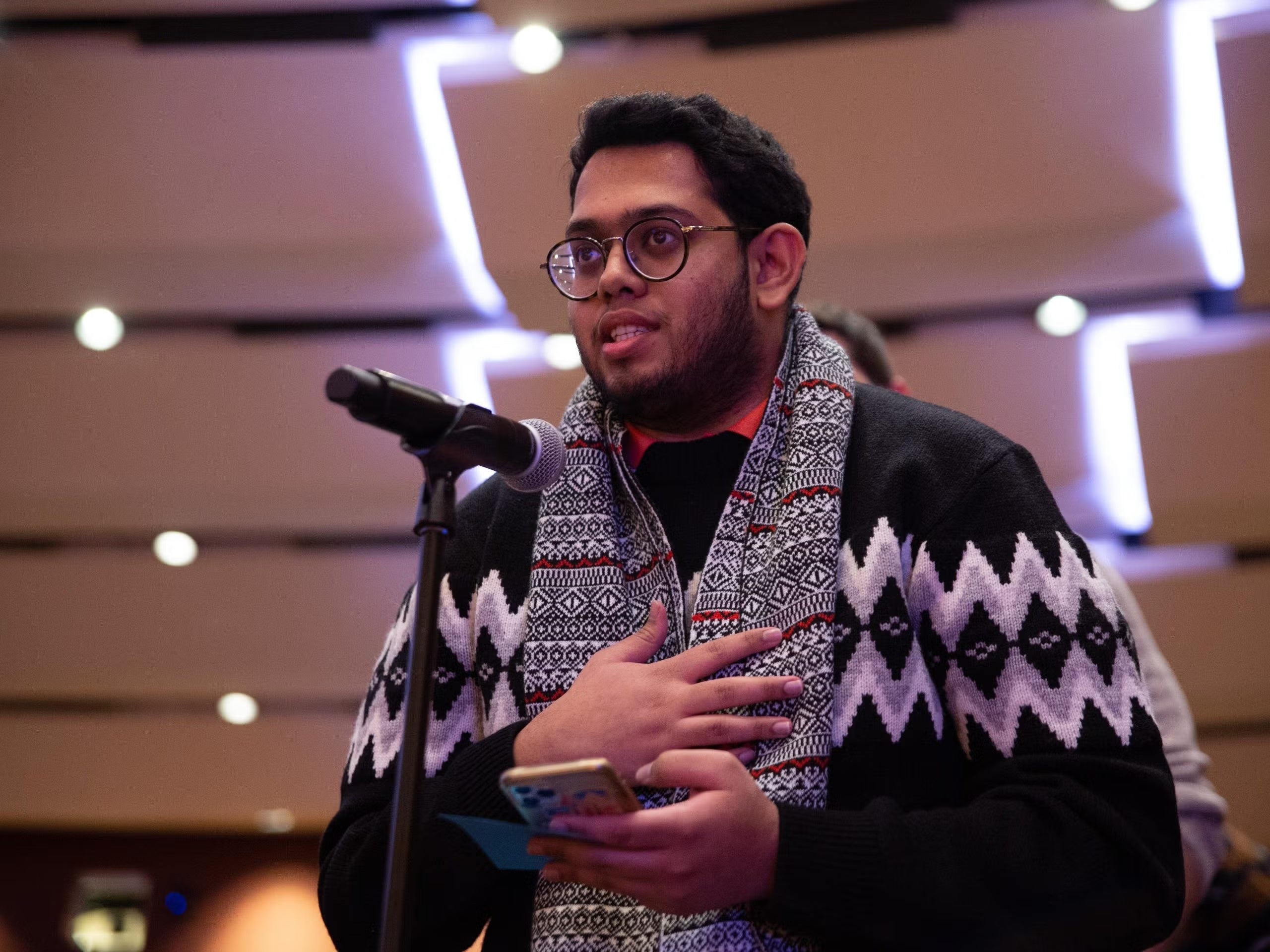 Man asking a question at a mic holding phone.
