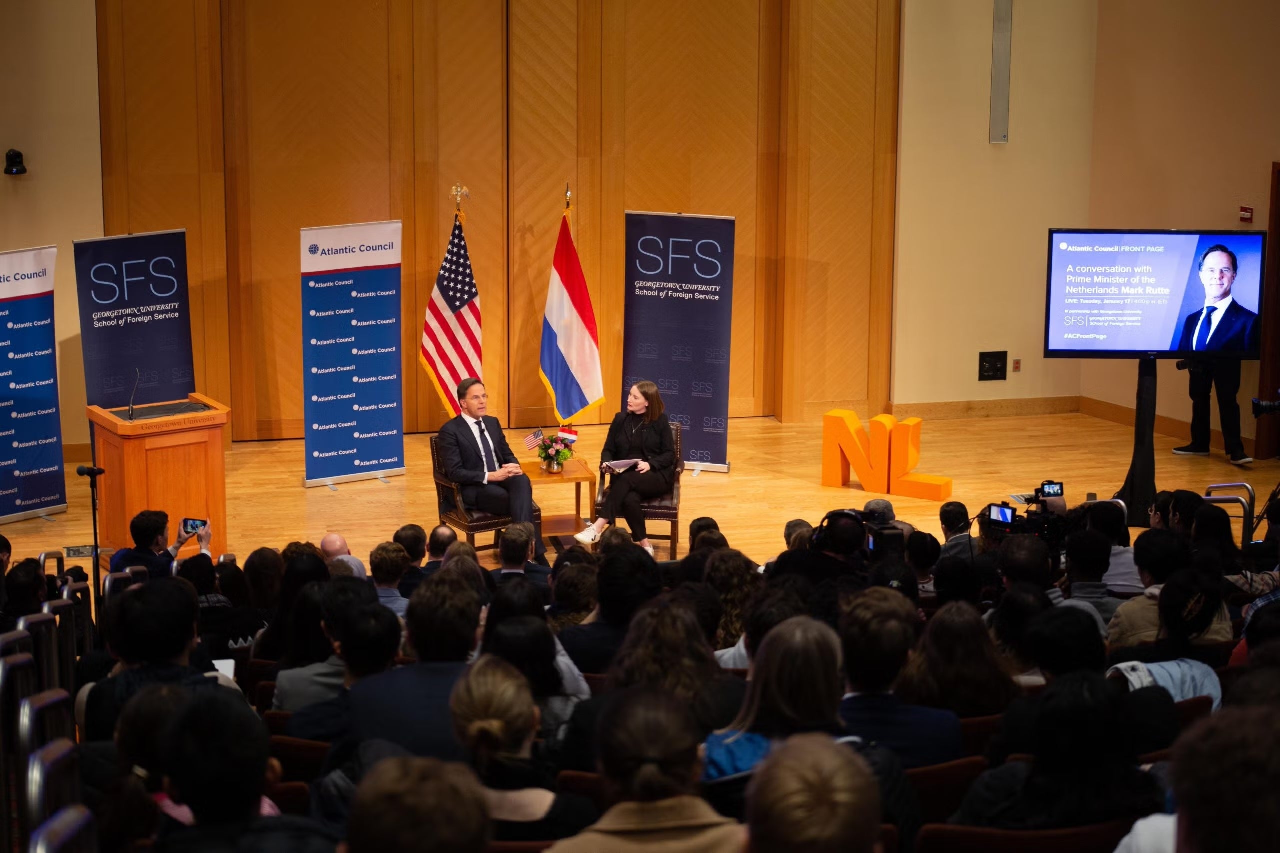Mark Rutte and Amy Mackinnon on-stage, with the American and Dutch flags in the background.