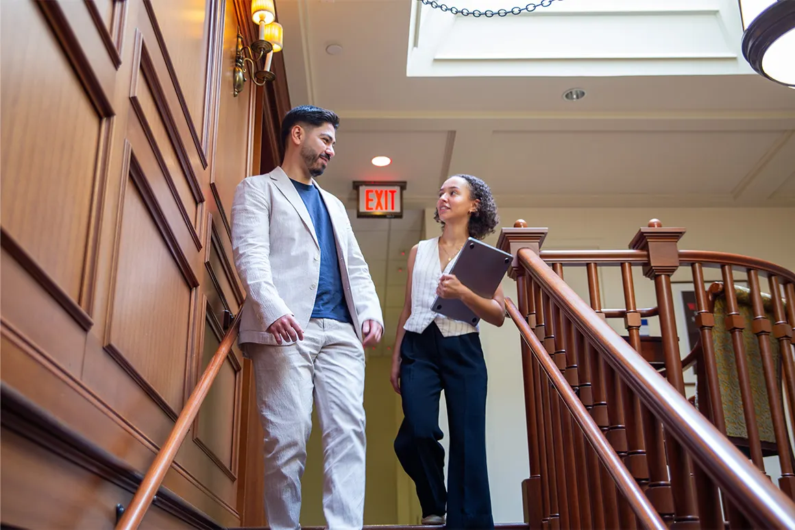 Two students going down steps and talking.