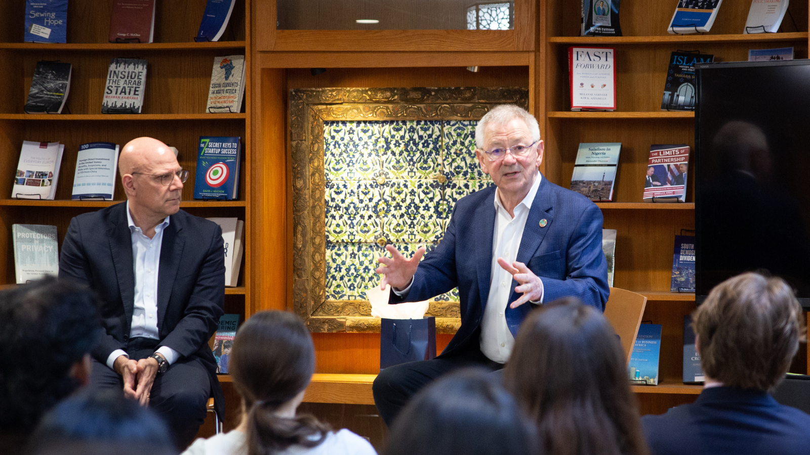 SFS Dean Joel Hellman and Distinguished Research Professor Andrew Steer talking to a line of four students with their backs to the camera.