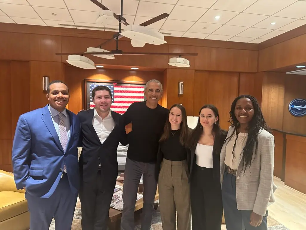 Group of six people posing for a photo in a professional setting, including former President Barack Obama